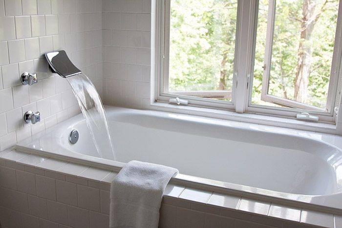 A Deep relaxing tub by an open window filling with water