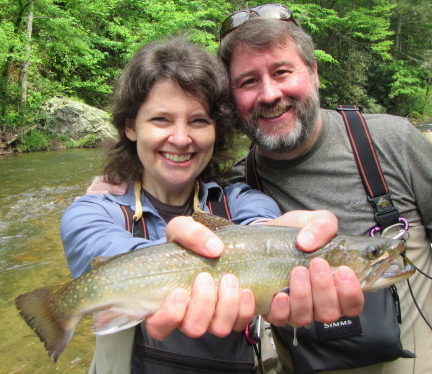 A couple holds a fish they caught fly fishing