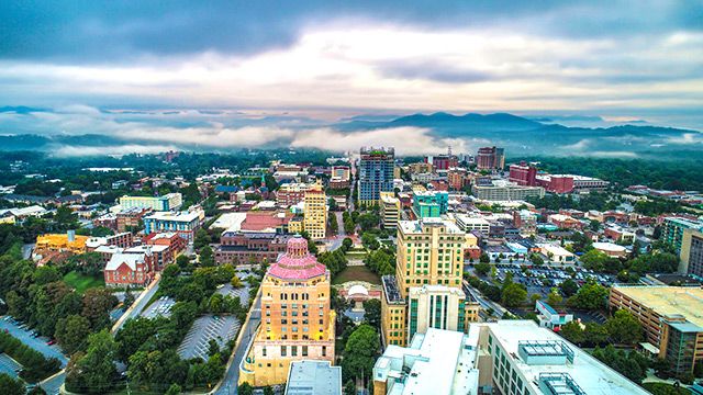 Downtown Asheville as seen from above, with the misty Blue Ridge Mountains
