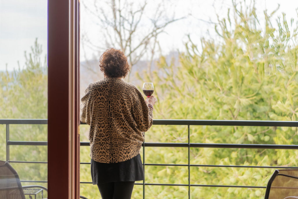 Woman with a glass of wine looking out at the mountains